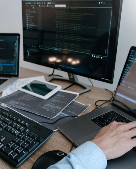 Desarrollador programando en múltiples pantallas con código en varios monitores y dispositivos en un entorno de trabajo tecnológico.